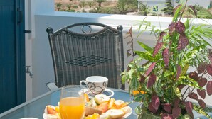 Un tavolo con un bicchiere di succo d'arancia, una tazza di caffè e un piatto di cibo, con vista su un paesaggio suggestivo che include mare e colline.
