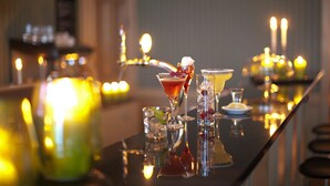 A bar area with a polished counter, glasses, and candles, suggesting a cozy ambiance.