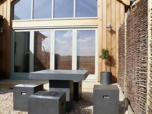 A patio area with a table and two speakers, a wooden fence, and a potted plant.