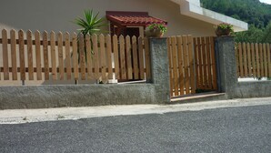A modern building with a sloped roof, a wooden picket fence, and two potted plants. - Omega House (Guardia Piemontese)