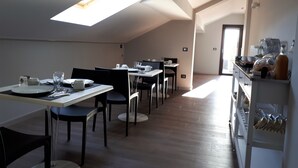 A dining area with tables and chairs, a kitchen area with appliances, and a skylight. - Etna Sunrise B&B (Zafferana Etnea)