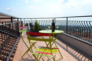 Un balcón con mesa y sillas, una botella de vino y vistas al paisaje.