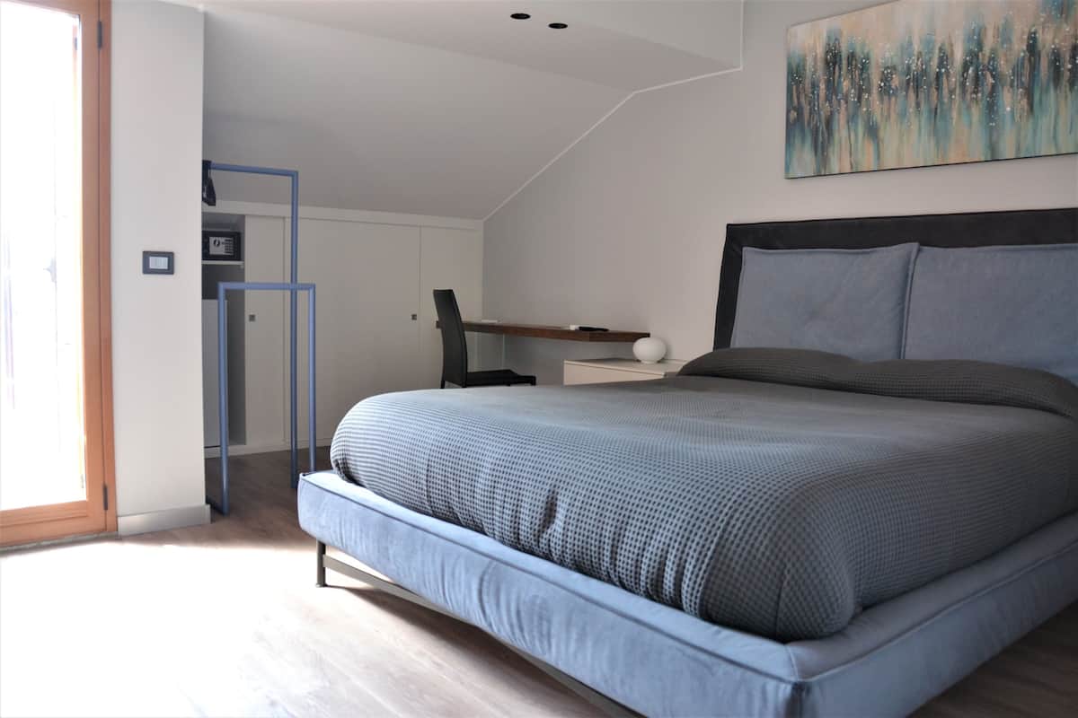 A bedroom with a large bed, a desk, and a chair.
