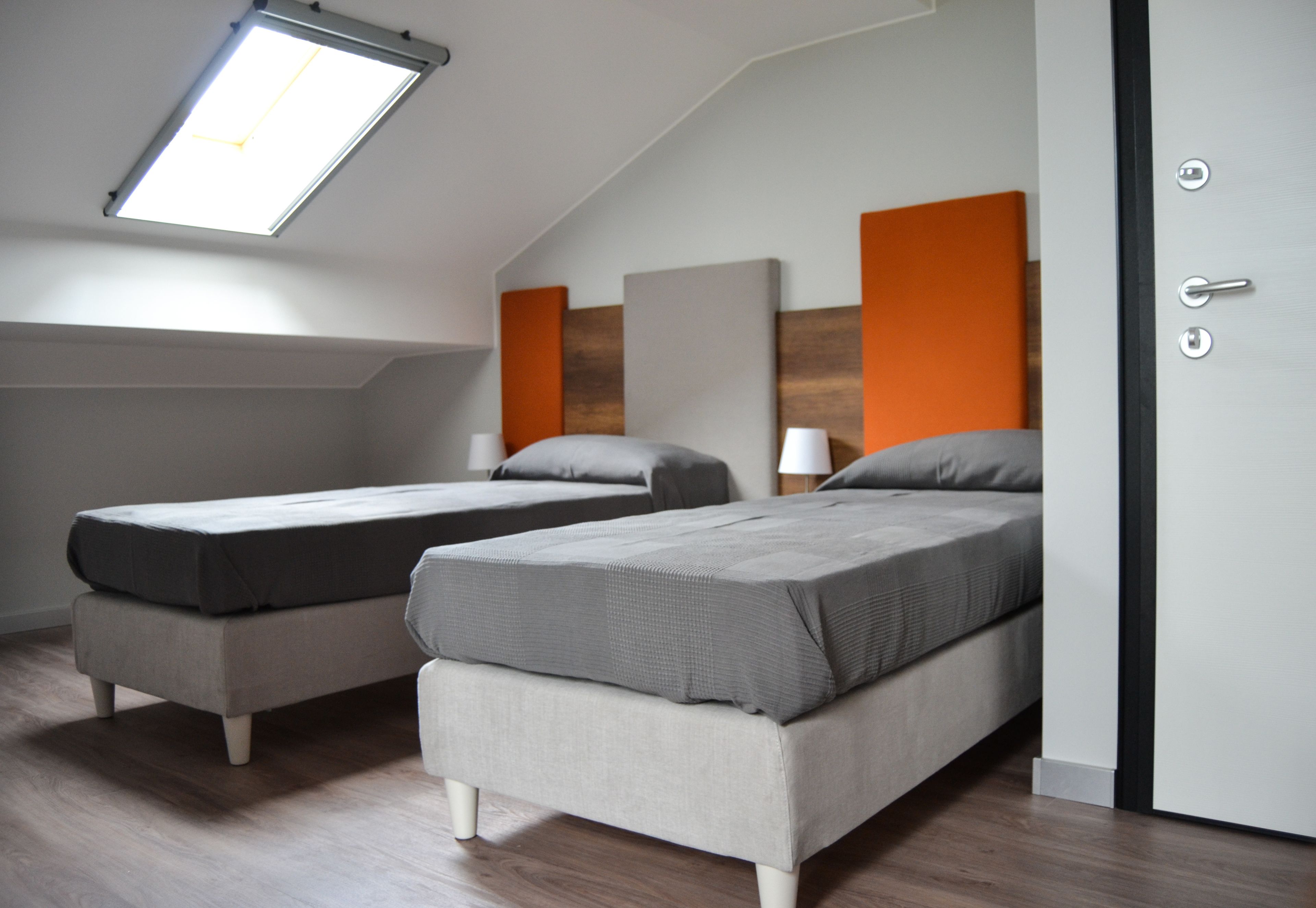 A room with two beds, a skylight, and a door with a handle.