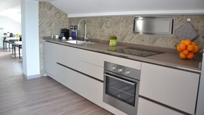 A modern kitchen with a built-in oven, a sink, and a backsplash with patterned tiles. - Etna Sunrise B&B (Zafferana Etnea)