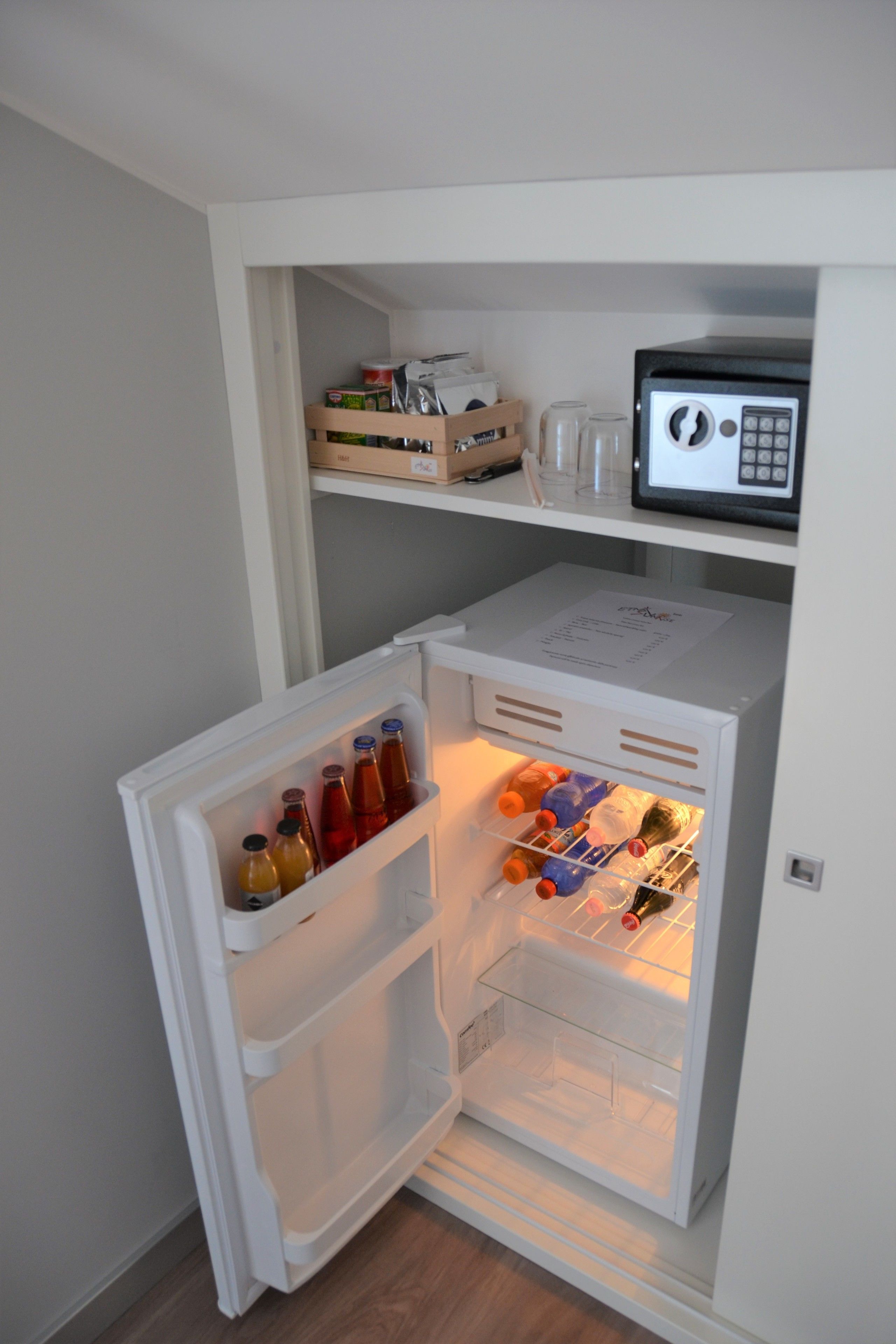 A compact refrigerator with a freezer compartment, containing various beverages and bottles.