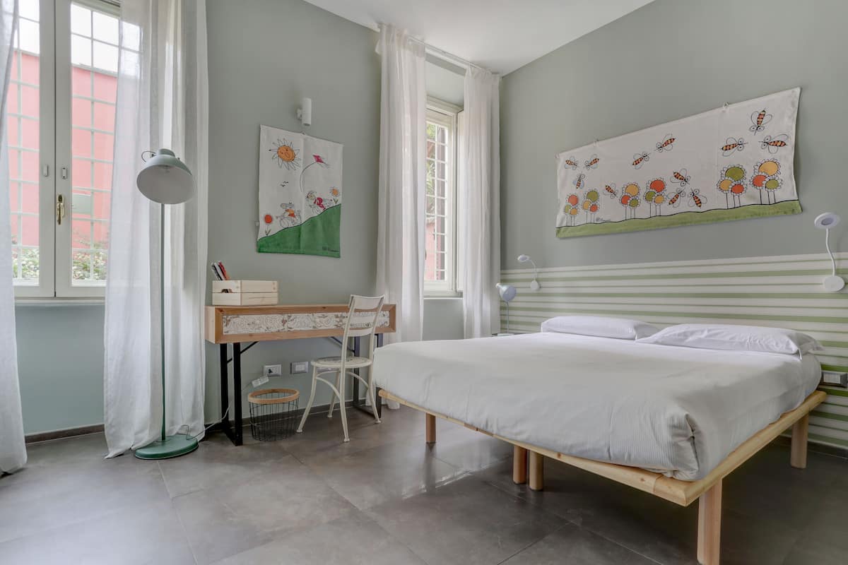 Un dormitorio con cama, escritorio, silla y ventana con cortinas.