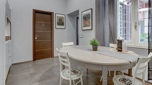 A dining area with a round table, white chairs, and framed artwork on the walls. - Appartamento Capo D'Africa 30 (Rome)