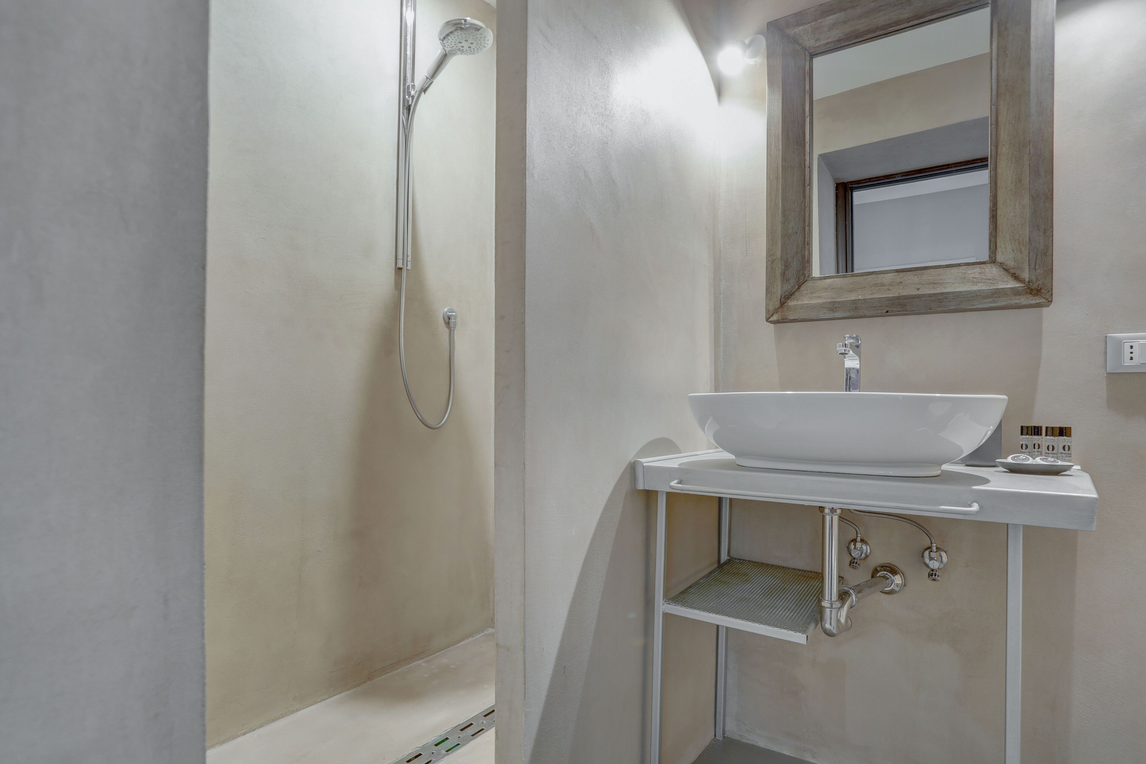 Un baño con lavamanos blanco, espejo y ducha.