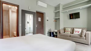 A hotel room with a large bed, a sofa, a TV mounted on the wall, and a small table with a kettle. - Appartamento Capo D'Africa 30 (Rome)