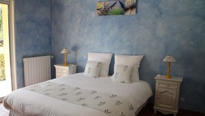 A bedroom with a large bed, two bedside tables with lamps, a radiator, and a wall-mounted artwork. - Chambres d'hôtes La Dryade (Tourves)