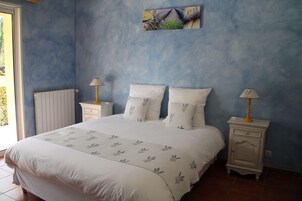 Quarto com uma cama grande, duas mesas de cabeceira com luminárias, um radiador e uma obra de arte pendurada na parede.