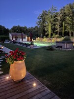 Um jardim bem cuidado com um deck de madeira, uma banheira de hidromassagem e um espaço de pátio com móveis para área externa.