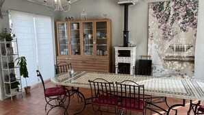 A dining area with a large table, chairs, a cabinet with glass doors, a fireplace, and a chandelier. - Chambres d'hôtes La Dryade (Tourves)