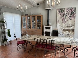 Uma sala de jantar com uma mesa grande, cadeiras, um armário com portas de vidro, lareira e um candelabro.