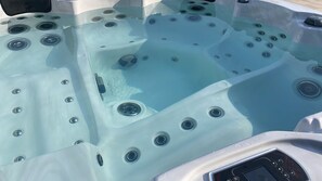 Een jacuzzi met meerdere jets, een bedieningspaneel en een afvoer.
