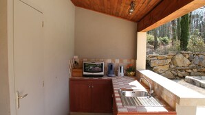 A compact kitchen with a stone countertop, a built-in sink, and wooden cabinets. - Chambres d'hôtes La Dryade (Tourves)