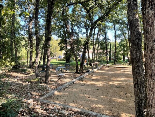 A campground with a dirt path, wooden benches, and a picnic table. - Chambres d'hôtes La Dryade (Tourves)