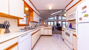 A kitchen with white cabinets, wooden accents, a dishwasher, a stove, and a refrigerator. - Simply Perfect - S Nags Head MP 19.5, 120 Yds to Beach, Ocean View, Community Pool, Tennis (South Nags Head)