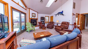 A spacious living room with a fireplace, leather chairs, a large sofa, and a television. - Simply Perfect - S Nags Head MP 19.5, 120 Yds to Beach, Ocean View, Community Pool, Tennis (South Nags Head)