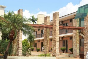 A multi-story building with brick and stone exterior, balconies, and palm trees. - Vancouver Hotel (Ribeirão Preto)