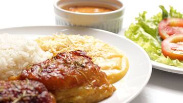 A plate with rice, a piece of meat, cheese, and a side salad.