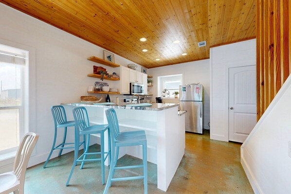 A modern kitchen with a central island, bar stools, and built-in appliances.