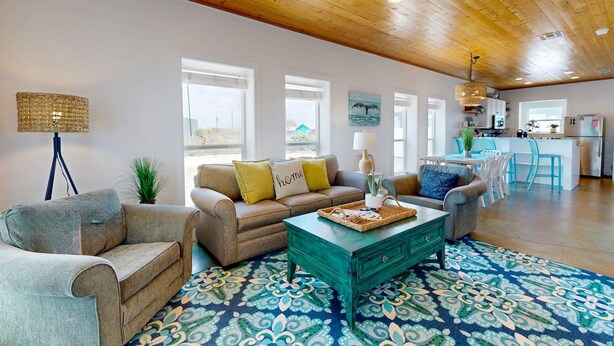 A spacious living room with a high ceiling, a sofa set, a coffee table, and a patterned rug. - Close to Beach, Pet Friendly and Shared Pool (Port Aransas)