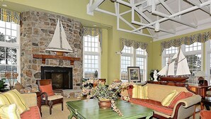 Un salon chaleureux avec une cheminée en pierre, des meubles en osier et une décoration sur le thème de la mer.