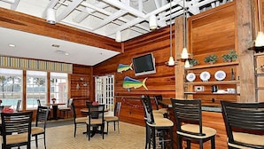 Un restaurant avec des murs en bois, une vue sur la piscine et un téléviseur fixé au mur.