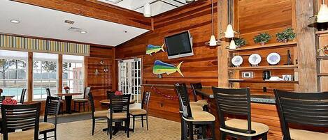 Ein Restaurant mit Holzwänden, Blick auf einen Pool und einem Fernseher an der Wand.