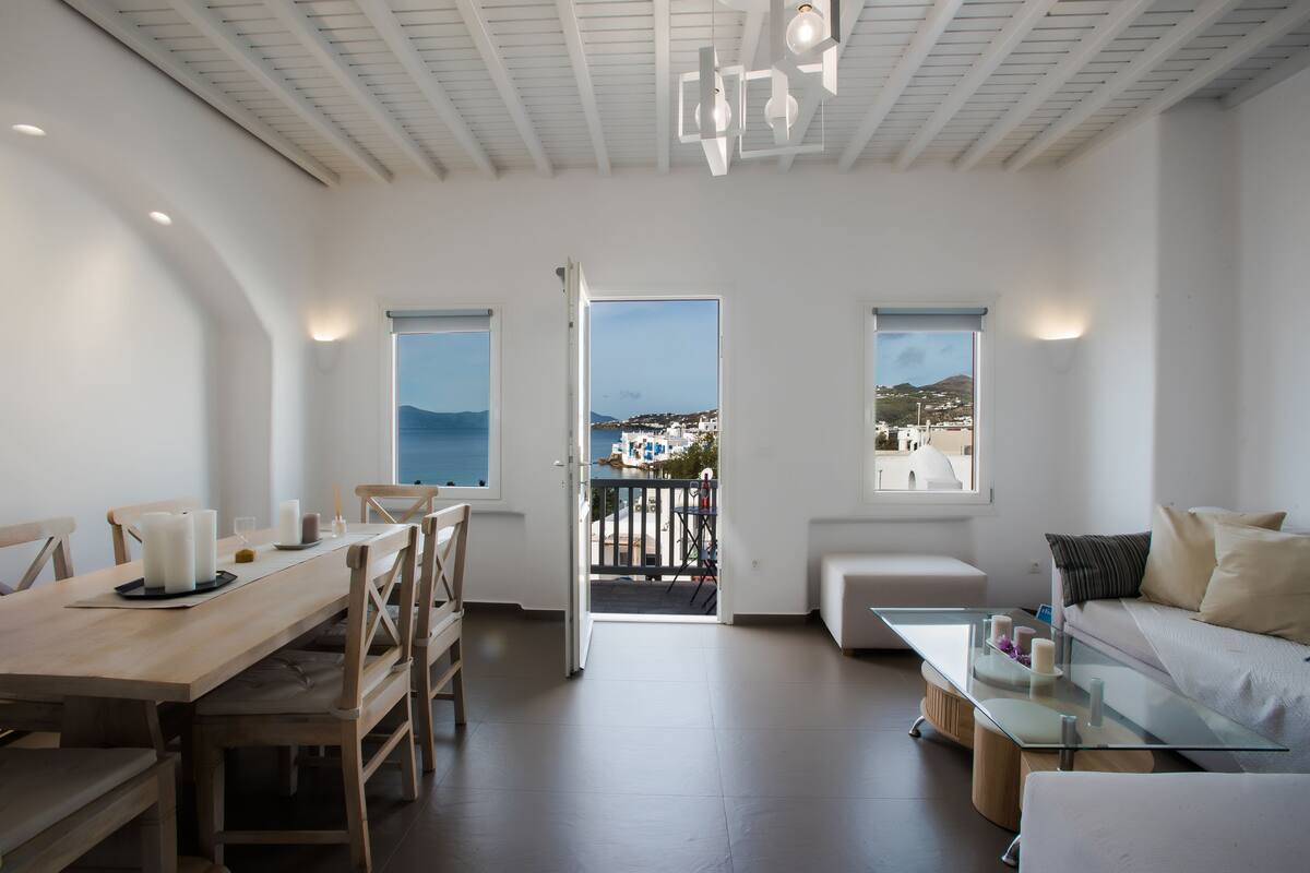 A spacious living area with a balcony, a dining table, and a sofa.