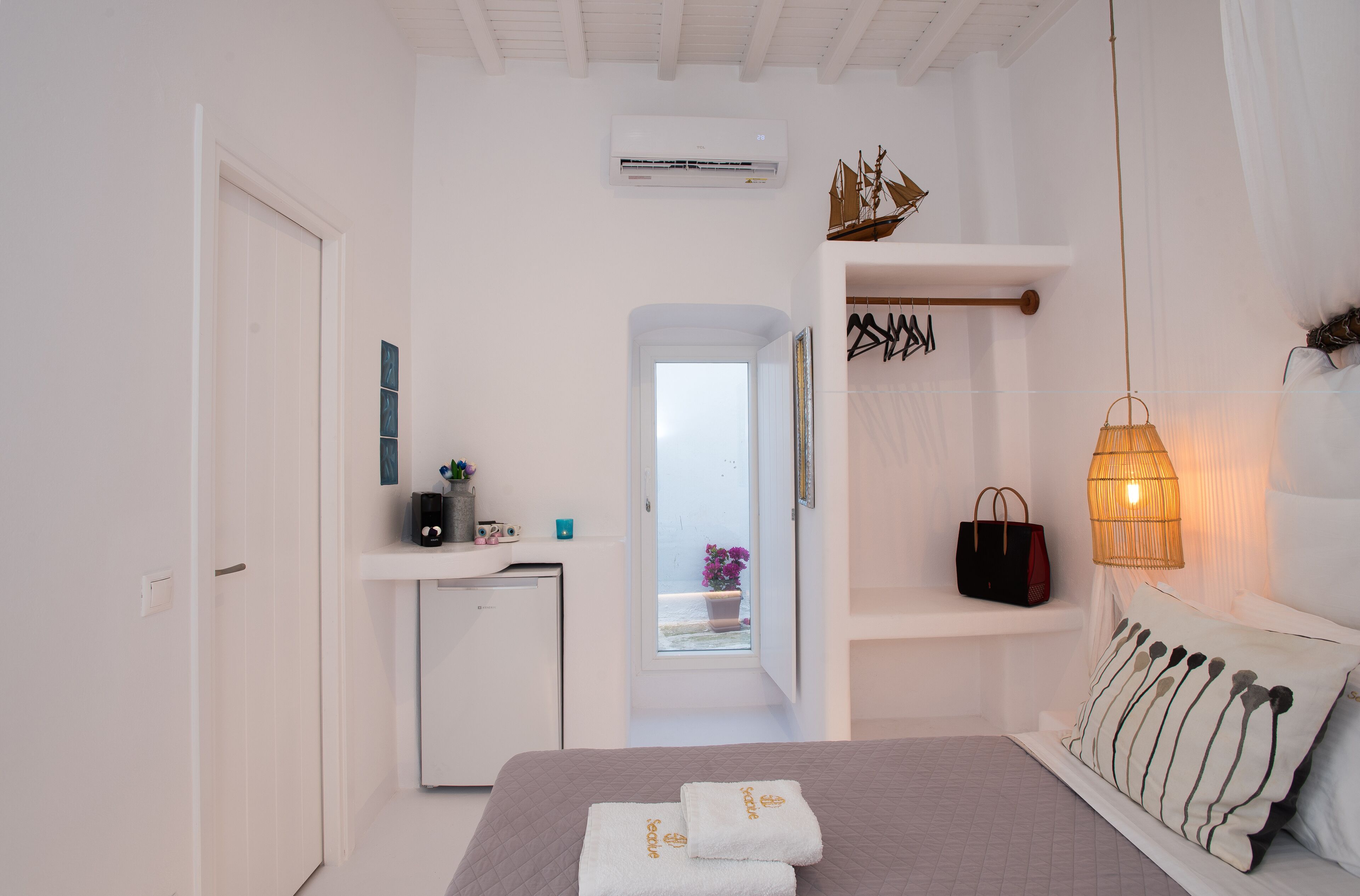 Une chambre à coucher comprenant un lit, une table de chevet, une commode, une fenêtre et une porte.