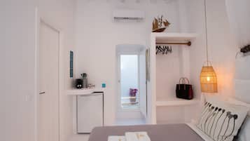 Un dormitorio con cama, mesita de noche, ventana y puerta.