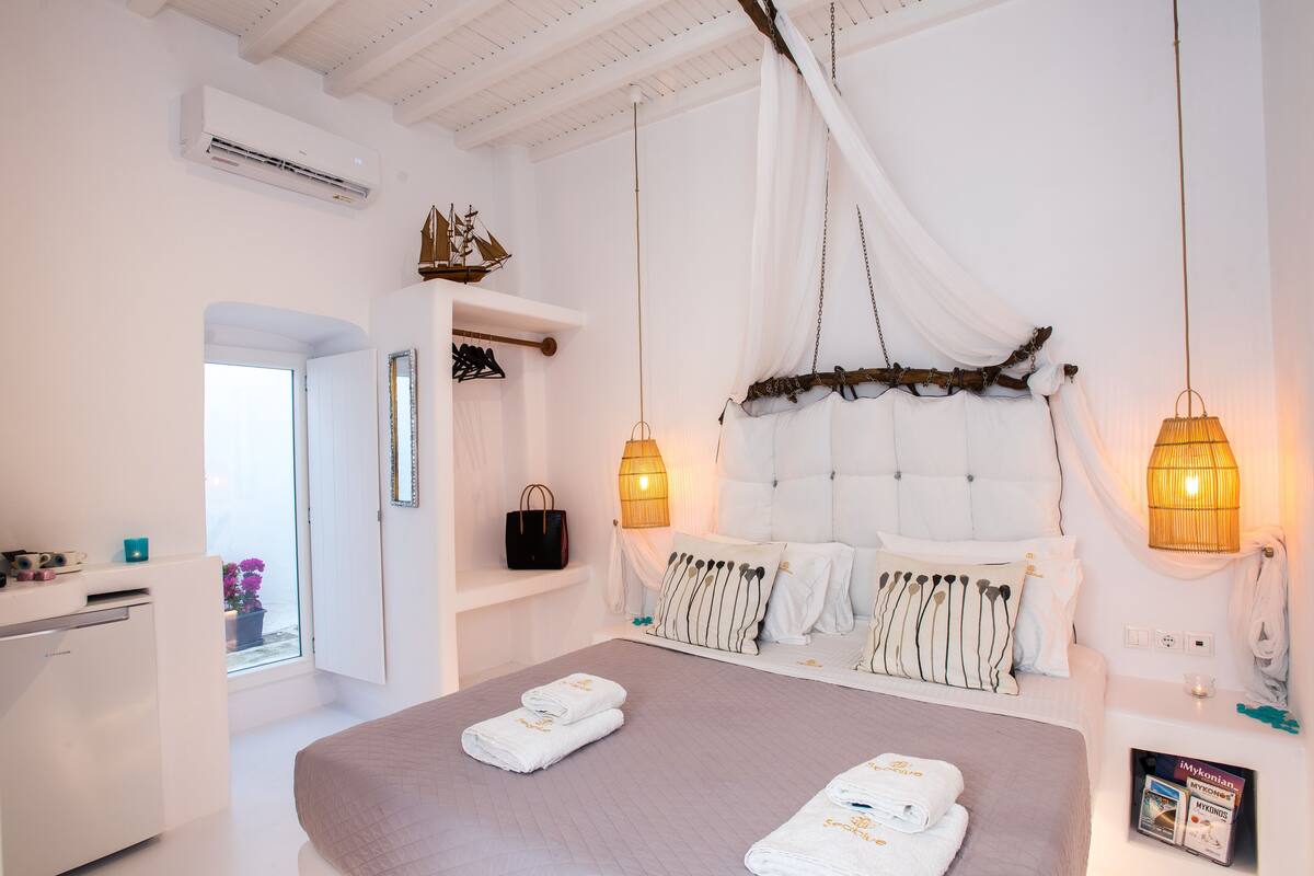 A bedroom with a large bed, bedside lamps, a wardrobe, and a window with a view.