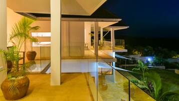 A modern house with a glass balcony overlooking a garden.