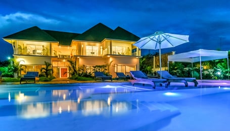 Una piscina al aire libre, sombrillas, sillones reclinables de piscina
