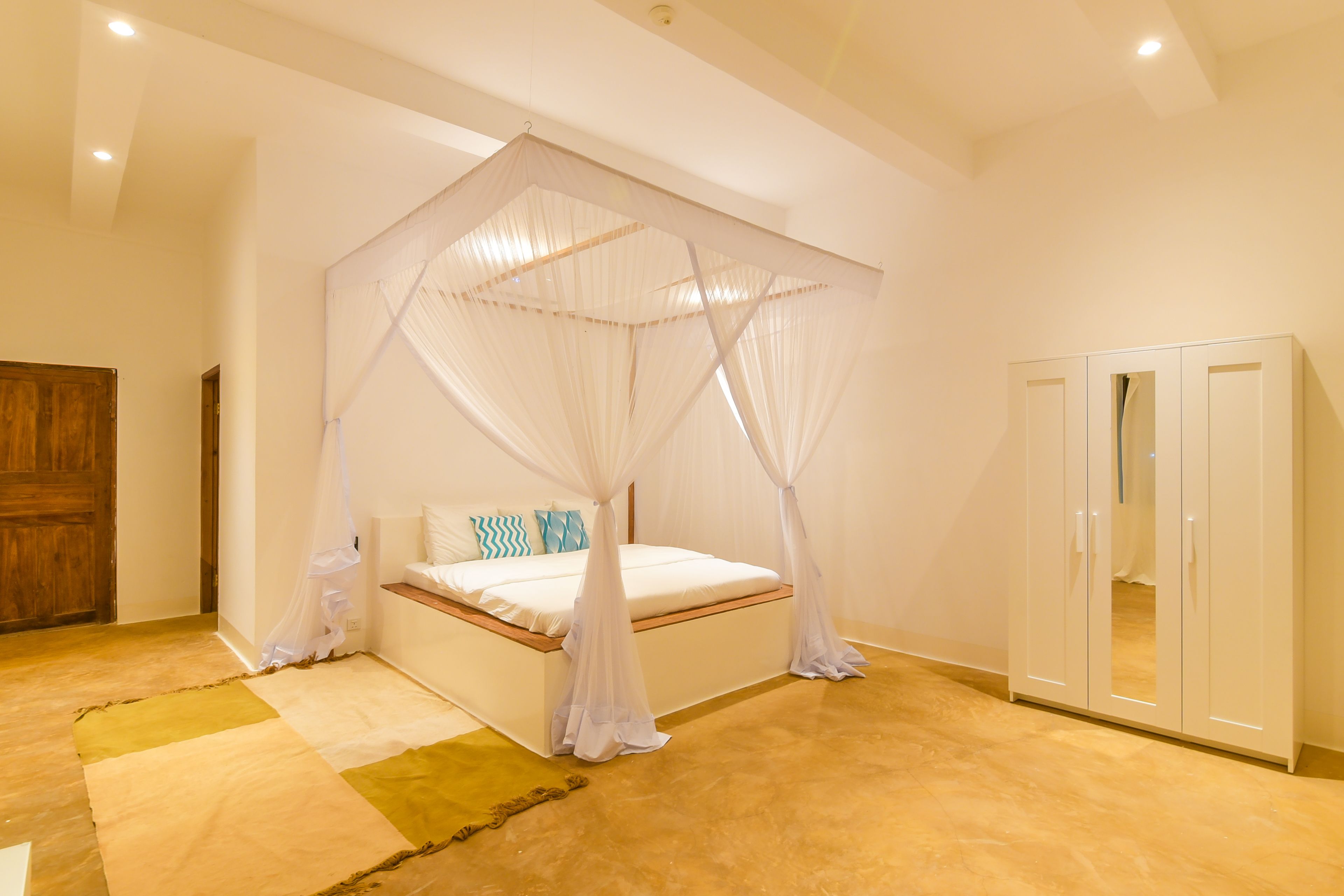 Ein Schlafzimmer mit Baldachinbett, Holztür und Kleiderschrank.