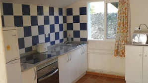 A compact kitchen with a checkered backsplash, a window with a floral curtain, and a built-in oven. - Ideal pets: apartment house with garden: for 2 people, for 3 ask (Nájera)
