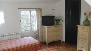 A bedroom with two beds, a TV on a wooden dresser, a window with curtains, and a door. - Ideal pets: apartment house with garden: for 2 people, for 3 ask (Nájera)