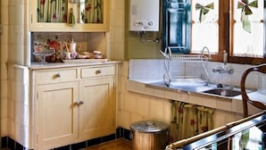 Una cocina con estufa integrada, pileta y ventana decorada con lazos.
