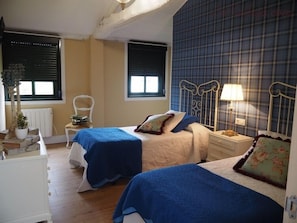 Ein Schlafzimmer mit zwei Betten, einem Sessel, einem Nachttisch und einer Heizung.