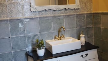 Een badkamer met een witte wastafel, een gouden kraan en een spiegel met een decoratieve lijst.