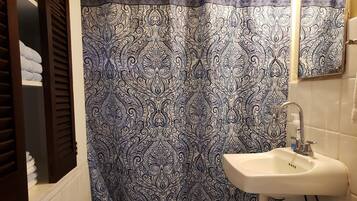 A bathroom with a patterned shower curtain, a sink, and a toilet.