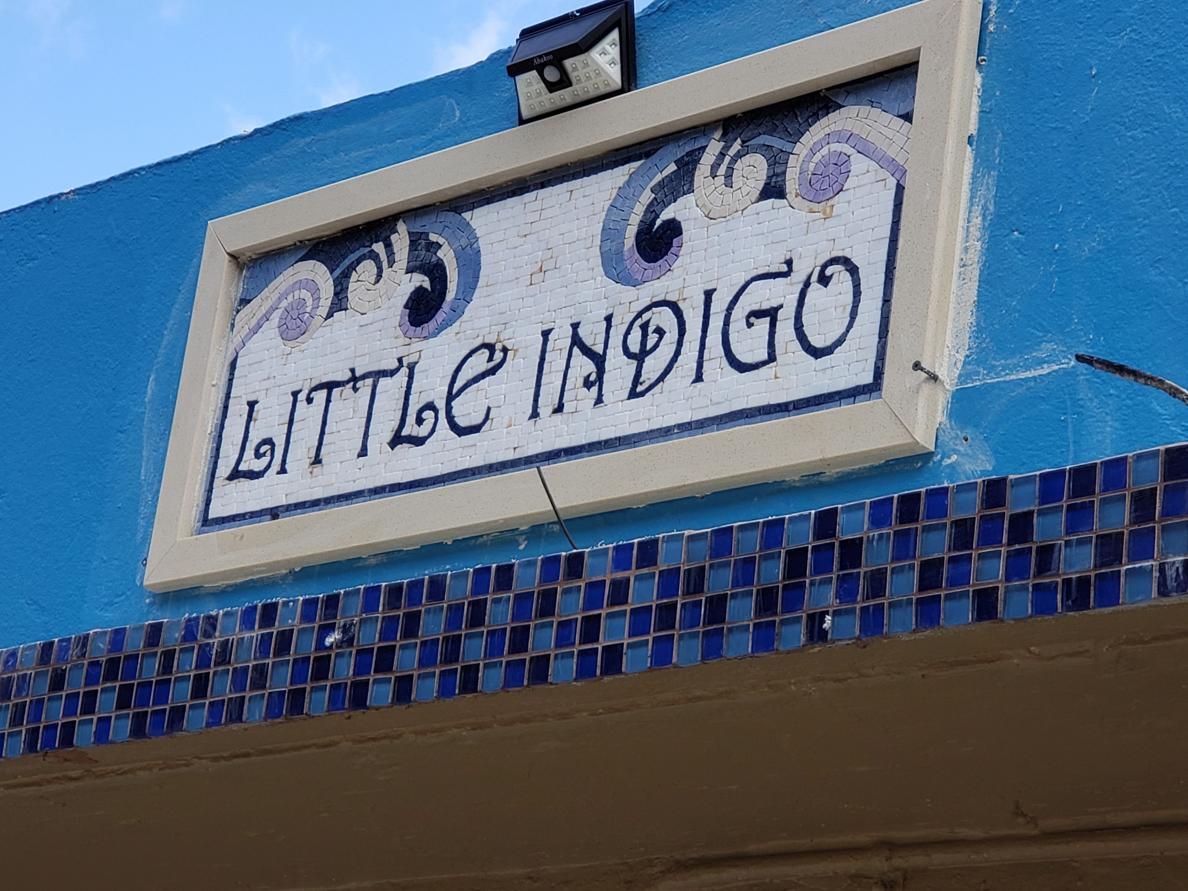 Ein Schild mit dem Schriftzug 'Little Indigo' an der Gebäudefassade.