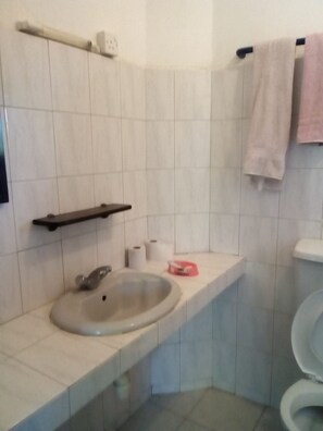 A bathroom with a sink, toilet, and towel rack. - Ashari Hotel (Mombasa)