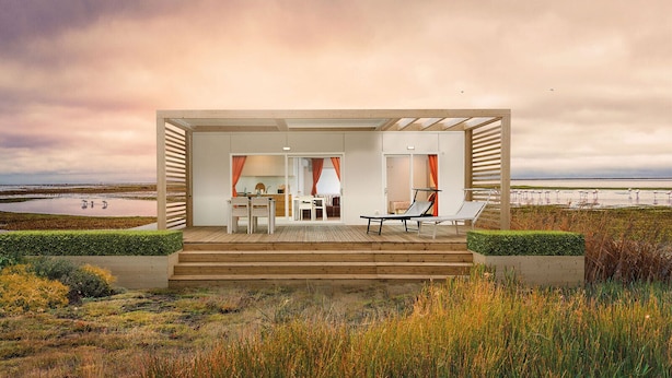 Een modern strandhuis met een houten terras, zitplaatsen buiten en uitzicht op zee.