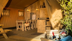 Een rustiek houten interieur met een eethoek, houten banken, een tafel met een mand en een bordje aan de muur.