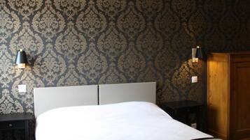 Ein Hotelzimmer mit einem großen Bett, zwei Nachttischen, einem Holzschrank und ornamentalem Wandpapier.