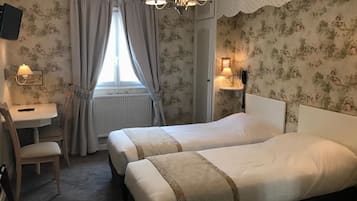 Habitación de hotel con dos camas, un escritorio y una silla.